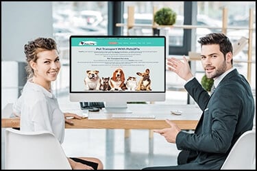 Business man and woman near a big computer screen showing us Pets2Fly's site