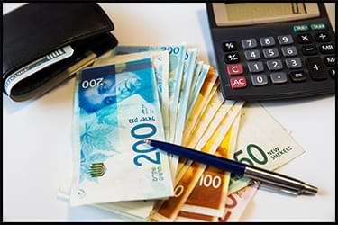 Shekel bills on a table - flight costs